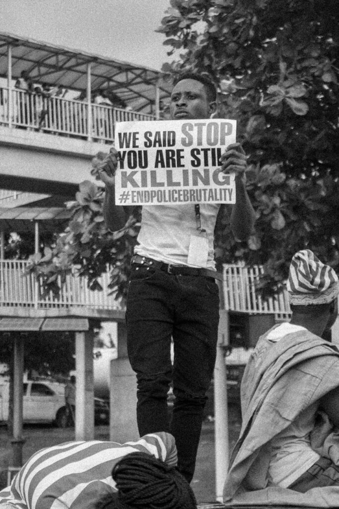 grayscale photo of man holding a paper with message